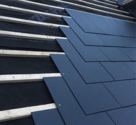 Dark roof slates being fitted over battens and roofing membrane