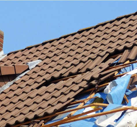 Damaged tiled roof with exposed battens and underlay