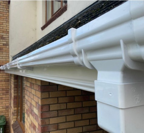 White guttering and fascia fitted along the edge of a brick house